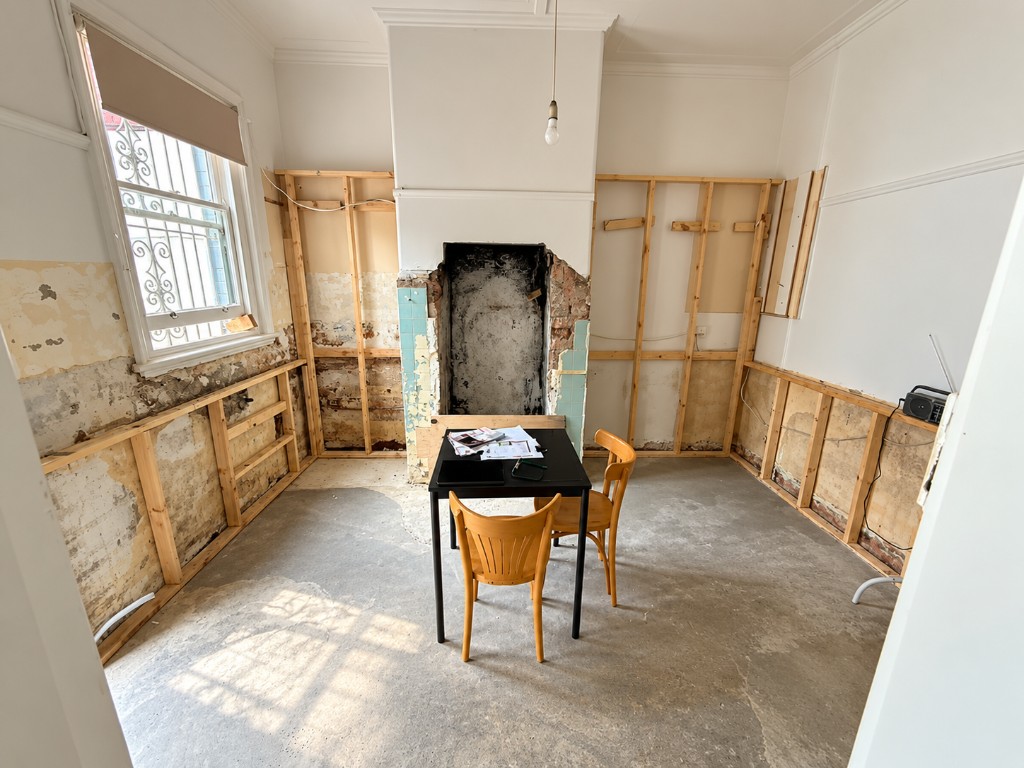 Unfinished room with stripped walls, exposed framing and an open fireplace