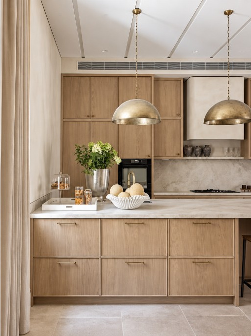 Warm oak kitchen in Melbourne with a stone island, framed cabinetry and brass pendant lights